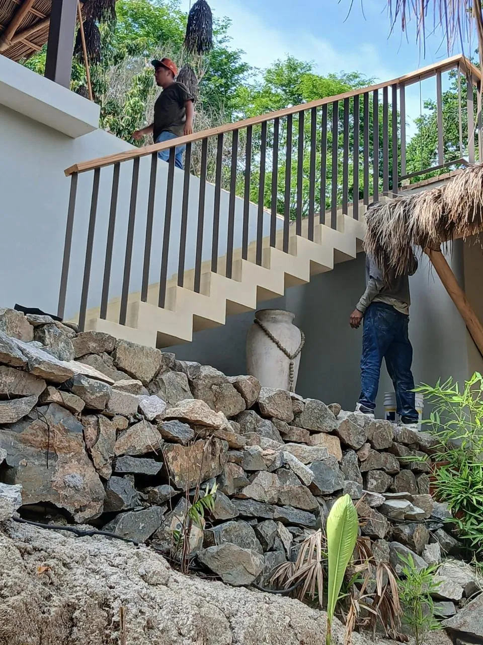 Escalera terminada con barandal de acero y madera sobre muro de piedra