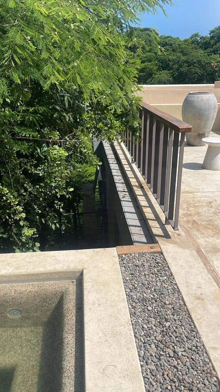 Pasillo con barandal y jardín junto a la alberca